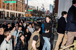 Young men and women stream into a church against New York skyline 