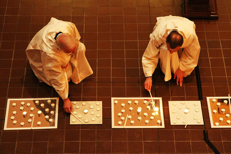 Brothers Ghislain (left) and Roger light the first candles.