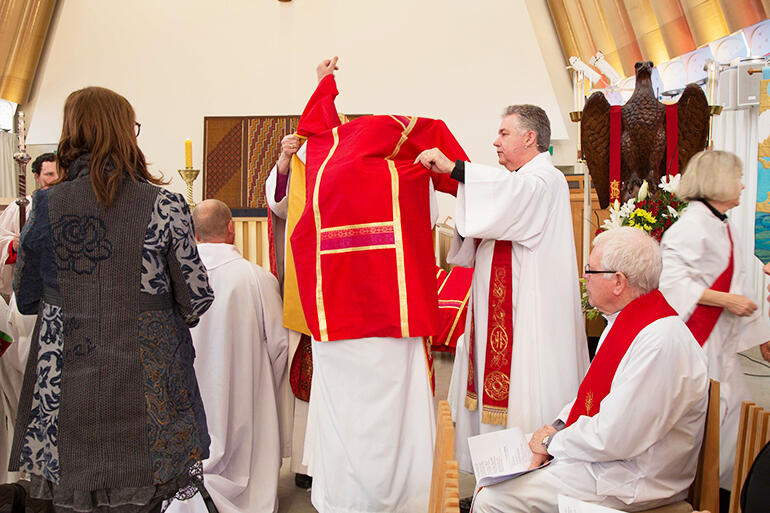 The Dean of Christchurch, Lawrence Kimberley, helps one of the new Deacons into their dalmatic.