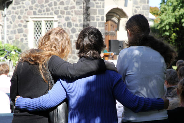 Reaching out in troubled times. Three of the folk who gathered yesterday at St Barnabas, Fendalton, for their open-air service.