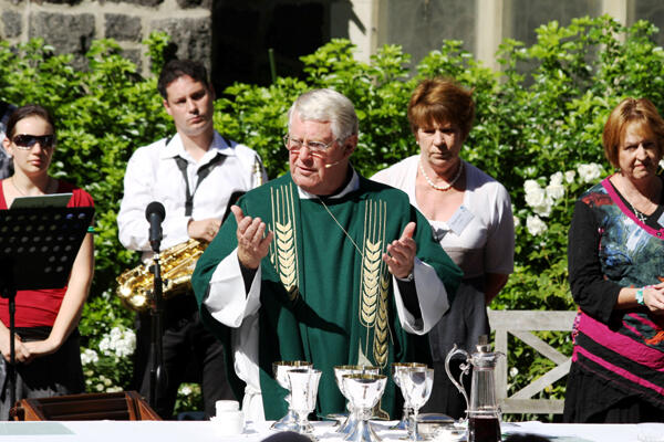 The Rev Philip Robinson, priest assistant at St Barnabas, invites his outdoor congregation to make their communion. The Rev Philip Robinson, priest assistant at St Barnabas, invites his outdoor congregation to make their communion.