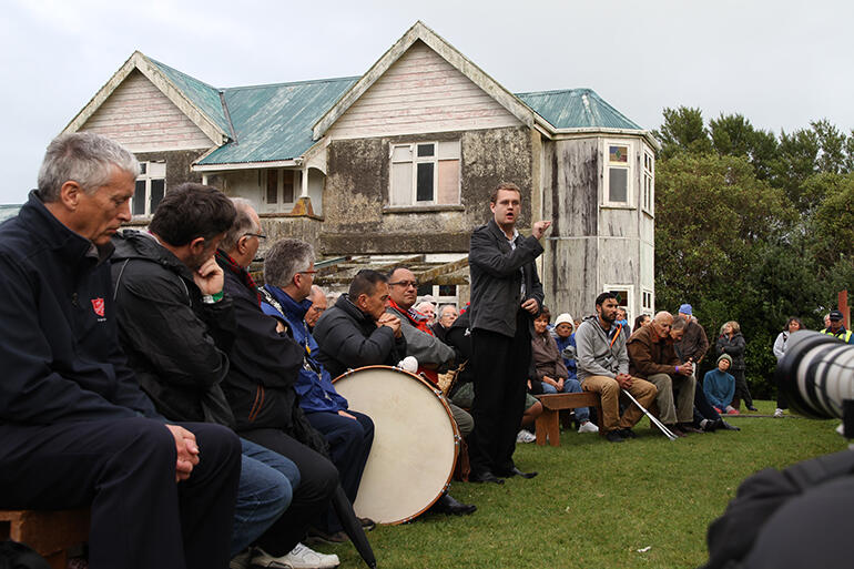 The manuhiri speak. That's the prophet Tohu Kakahi's home in the background.