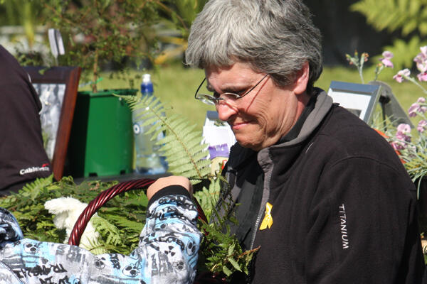The Rev Marge Tefft, Vicar of Holy Trinity, Greymouth, distributing fern fronds to the mourners at Omoto Racecourse.