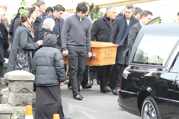 Sir Paul is borne from the hearse, and taken towards the steps leading into the church.