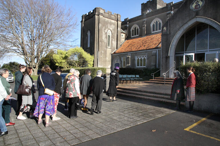 Whaea Tia leads manuhiri up the cathedral steps during the pōwhiri. Whaea Tia leads manuhiri up the cathedral steps during the pōwhiri.