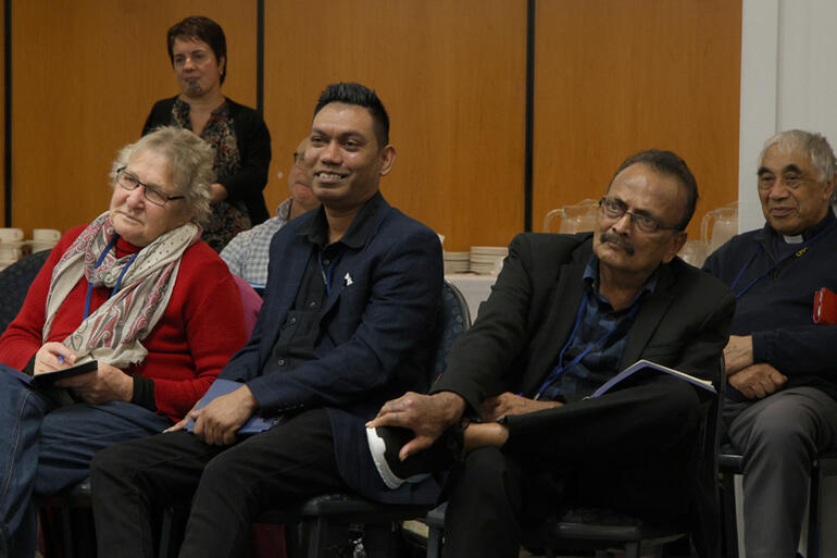 Jenny Campbell, Sudesh Chand and Keshwan Achari lean in as a presenter speaks during the Summit.