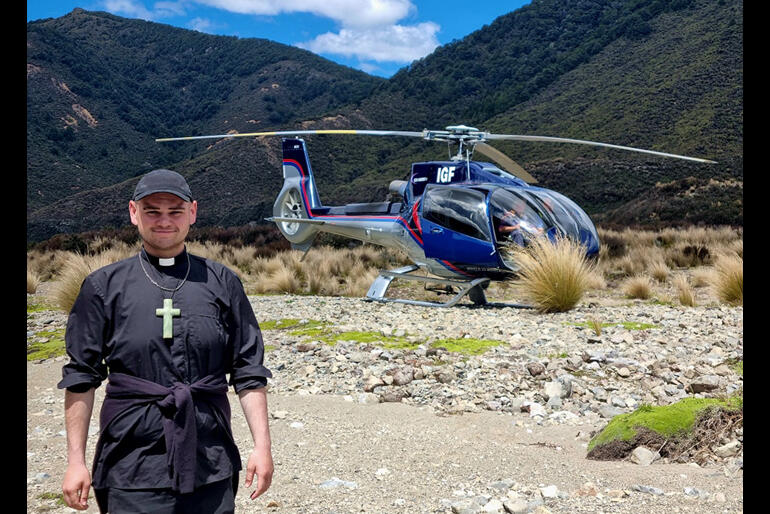 Rev Zhane Tahau Whelan stands with the helicopter that he and Ngāti Kahungungu leaders flew in to bless the affected area.
