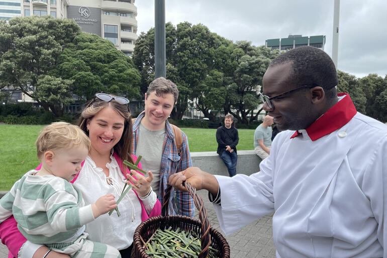 A Cathedral server distributes harakeke palm crosses outside Wellington's Cathedral of St Paul, Palm Sunday 2026.