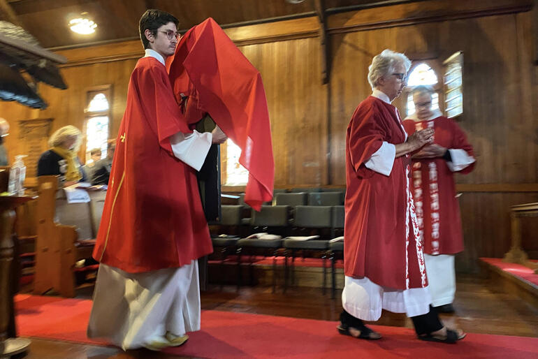 A server at St Barnabas Anglican Church in Roseneath Wellington processes the cross into the church on Good Friday 2026.