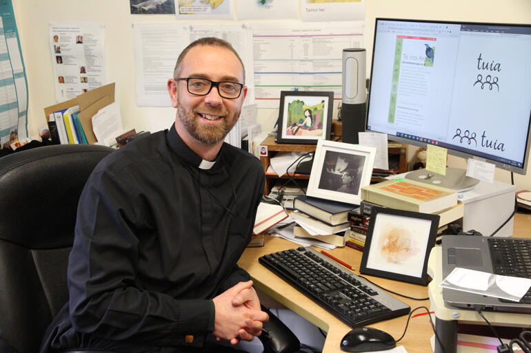 Rev Stephen Black brings up the logo and a mobile screenshot of the Tuia app at his former Ministry Educator's desk in Hamilton.