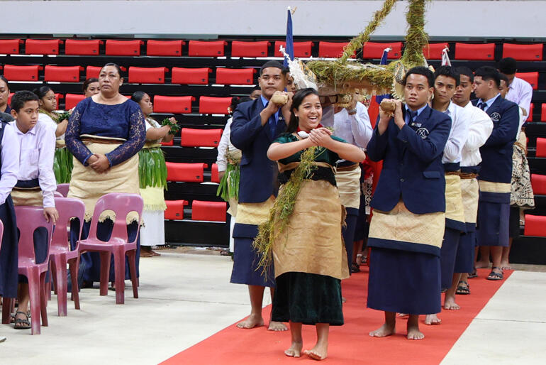 Young Tongan Anglicans carry the Gospel forward atop a wooden vaka.