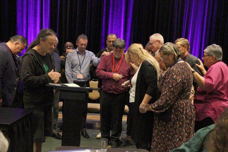 Bishops and delegates gather to pray for Archbishop Philip following the vote of thanks for his service as Te Hīnota Whānui president.