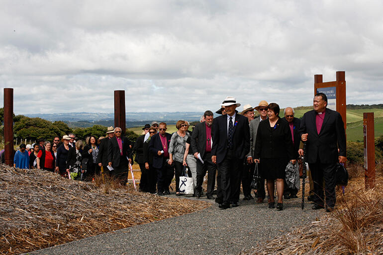 As the clouds begin to burn off, Bishop Kito Pikaahu leads the Governor General and manuhiri to the powhiri. As the clouds begin to burn off, Bishop Kito Pikaahu leads the Governor General and manuhiri to the powhiri.