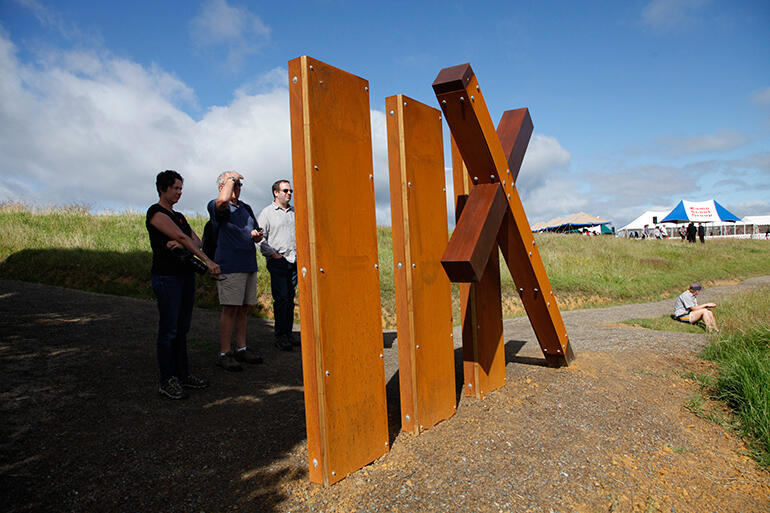 Visitors read the inscriptions on one of the new 'way stations' on the walkway down to Oihi Beach and the Marsden Cross.