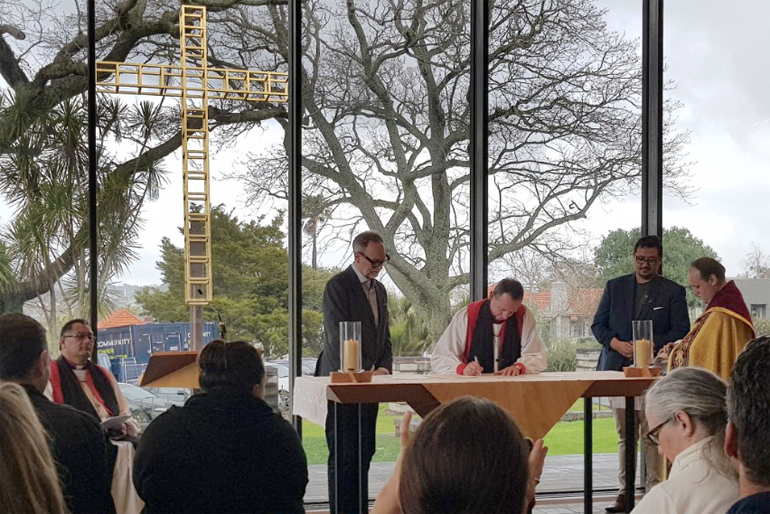 Bishop Ross Bay signs alongside Museum CEO David Gaimster (L) and Te Ariki Tamaroa Whatumoana (R), backed by Bishop Te Kitohi Pikaahu. 