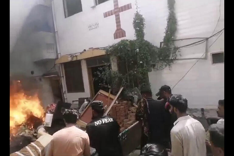 People gather in the street outside a church set on fire by angry mobs in Pakistan. Image: Bishop Azad Marshall on X.