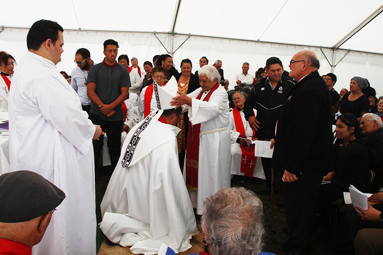 The Rev Rose Stainton places the mitre on the new bishop.