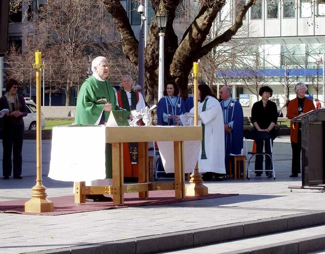 Dean Peter Beck leads the Great Thanksgiving during the Sunday morning open-air Eucharist in Cathedral Square. Dean Peter Beck leads the Great Thanksgiving during the Sunday morning open-air Eucharist in Cathedral Square.