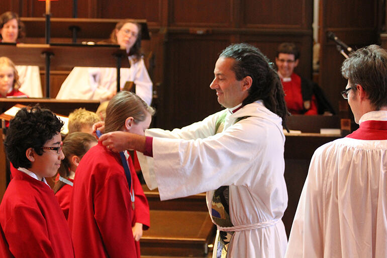 The bishop confers ribbons that mark choral achievement on some of the young cathedral choristers.