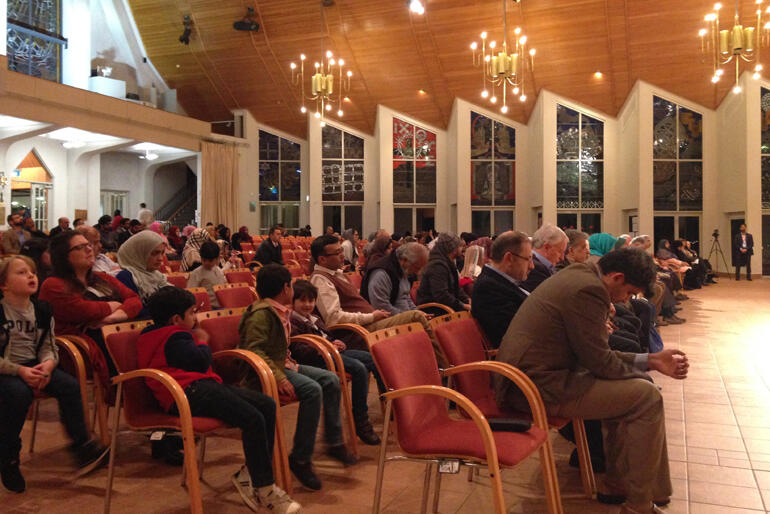 Shia Muslim guests bow heads as Bishop Ross Bay leads the two communities in prayer at the close of the Iftar event.