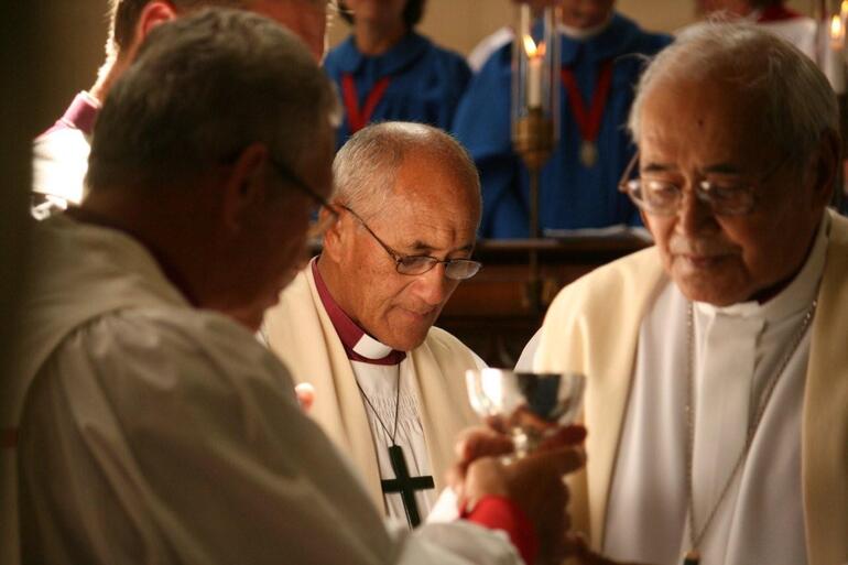 Bishop Muru Walters reflects, while Archbishop Brown Turei serves the chalice to Bishop Ngarahu Katene.