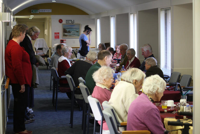 Bishop Matthews says grace for the Churchill Courts residents, as they prepare to eat their evening meal in a corridor. Bishop Matthews says grace for the Churchill Courts residents, as they prepare to eat their evening meal in a corridor.