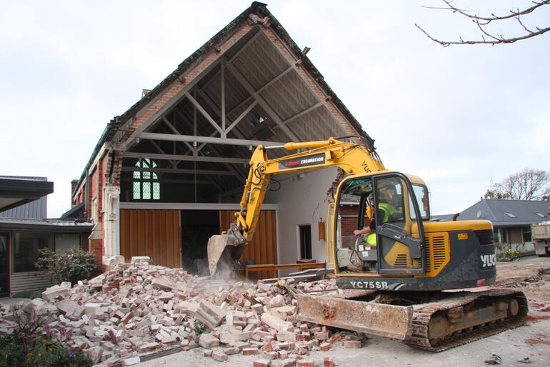 The excavator drags the fallen bricks of the Churchill Courts chapel into a pile, ready to be carted away. The excavator drags the fallen bricks of the Churchill Courts chapel into a pile, ready to be carted away.