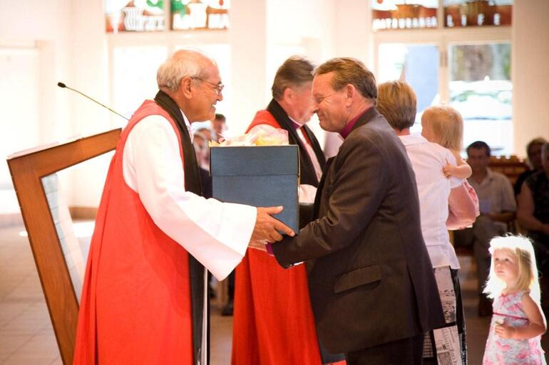 Archbishop Brown present Bishop John with a farewell gift. Bishop John's wife Marion and grandchildren are in the background.