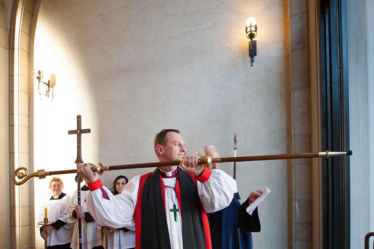 Bishop Ross knocks three times on a glass door that joins the new chapel with a cathedral ambulatory.