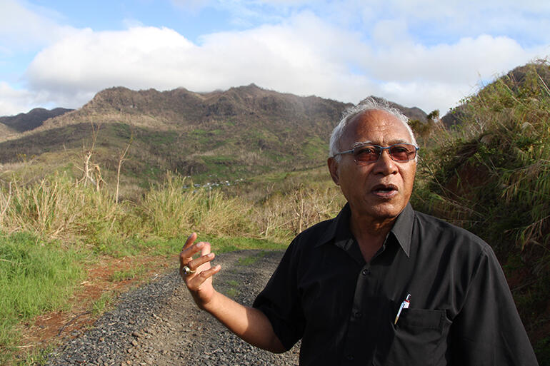 Archbishop Winston Halapua stopped on the road into Maniava to explain the history of the settlement - which can just be seen above his hand.