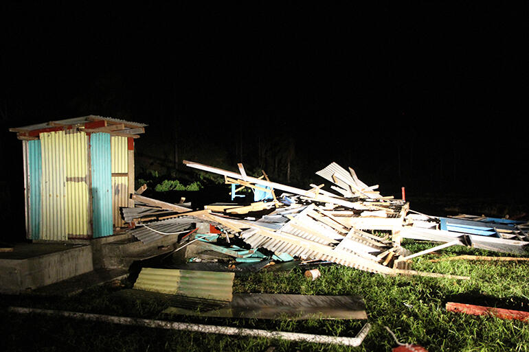 Car headlights pick out the fallen playcentre at the Wainaloka settlement, near Levuka, on the island of Ovalau.