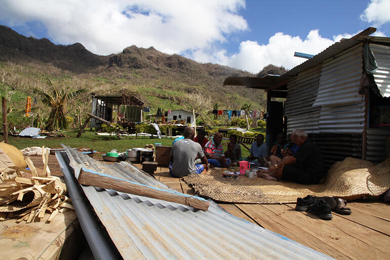 Chief Mosese Kakaramu telling what happened amidst the ruins of his house. The shelter at right has been built since the cyclone.