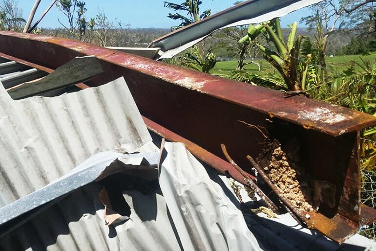 Building down - and a reinforced steel girder, torn from its moorings, sits atop a heap of buckled corrugated iron.