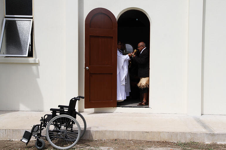 Kolofo'ou district officer Faiva Tu'ifua receives the cup, as seen from outside the church.