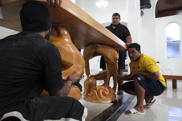 Young men from the carving company manoeuvre the new altar into place on Friday evening.