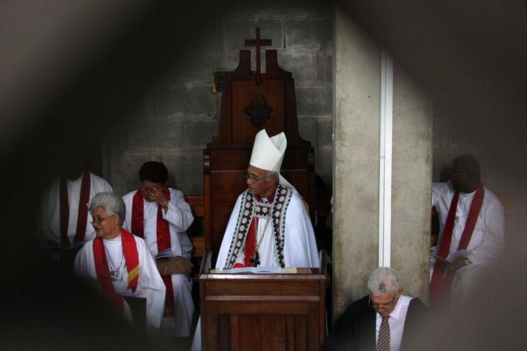 Archbishop Winston seated in his cathedra - as seen through the masonry grill of the mezzanine gallery.