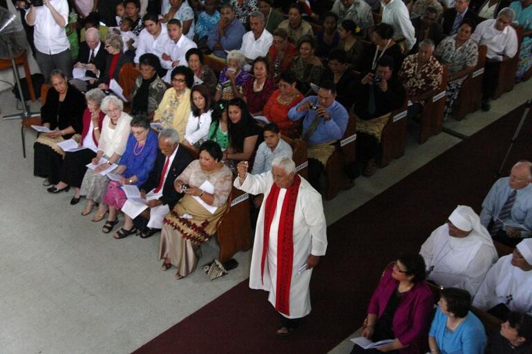 Archdeacon Richard Schwalger of Samoa holds the episcopal ring high as he moves towards Bishop Winston.