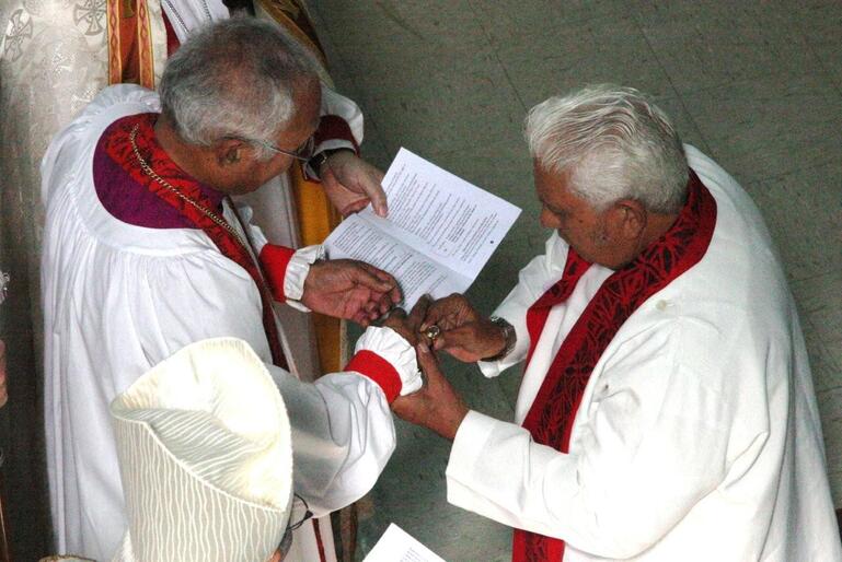 Archdeacon Schwalger places the episcopal ring on Bishop Winston's finger.