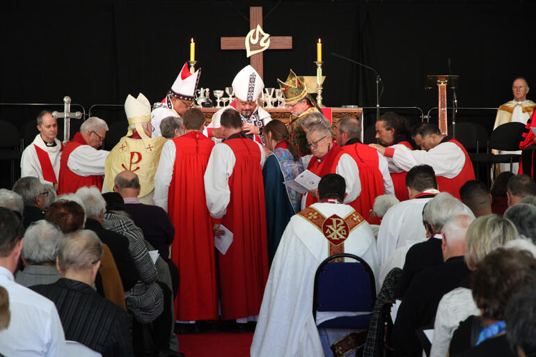 Bishops gather around with Bishop Waitohiariki at the centre, to ordain her as a bishop of the church.