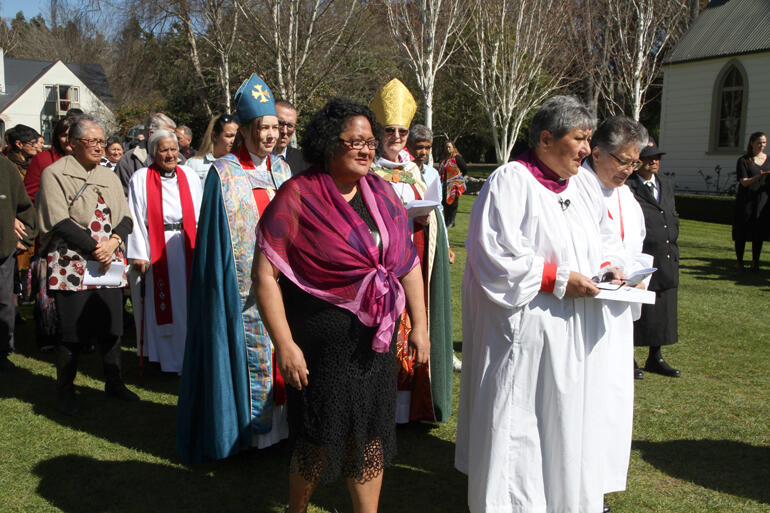 Waitohiariki Quayle processes toward the worship marquee with Rathkeale College chapel in the background.