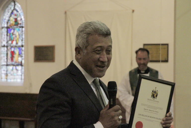 John Walters holds Bishop Muru Walters' certificate as life fellow of Te Maru Pūmanawa - Selwyn College, as College chaplain Rev M. Wallace looks on.
