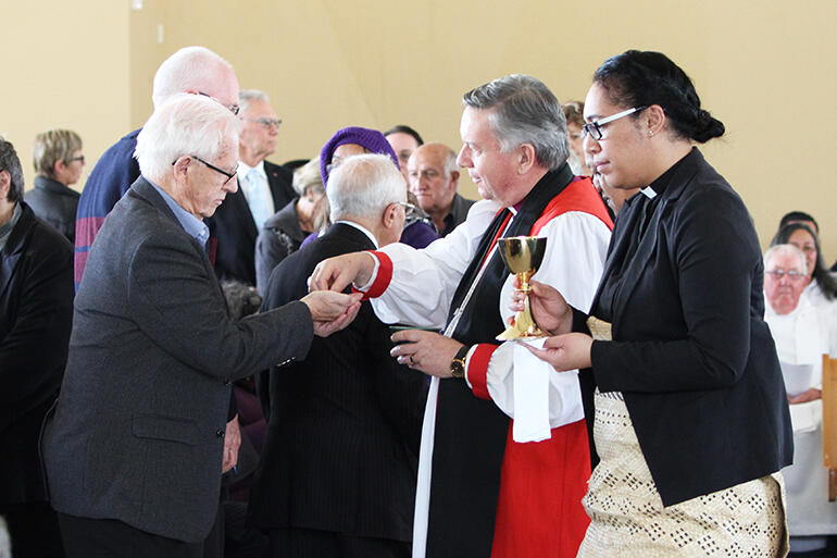Archbishop Sir David Moxon serves the host - while the Rev Mele Prescott waits.