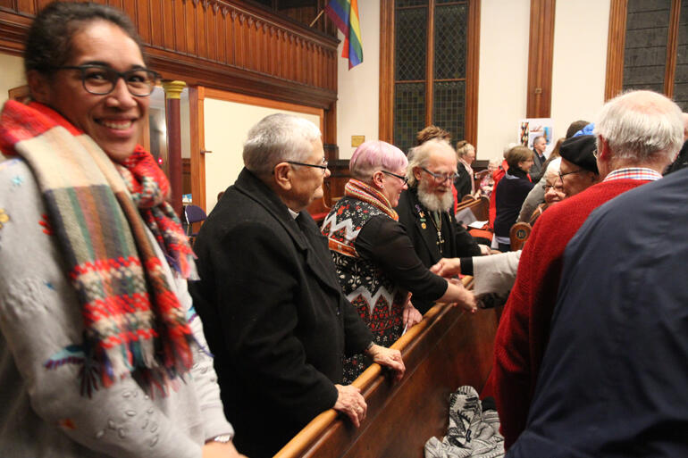 Rev Mele Prescott turns to the camera as her pew mates pass the peace. Rev Mele Prescott turns to the camera as her pew mates pass the peace.