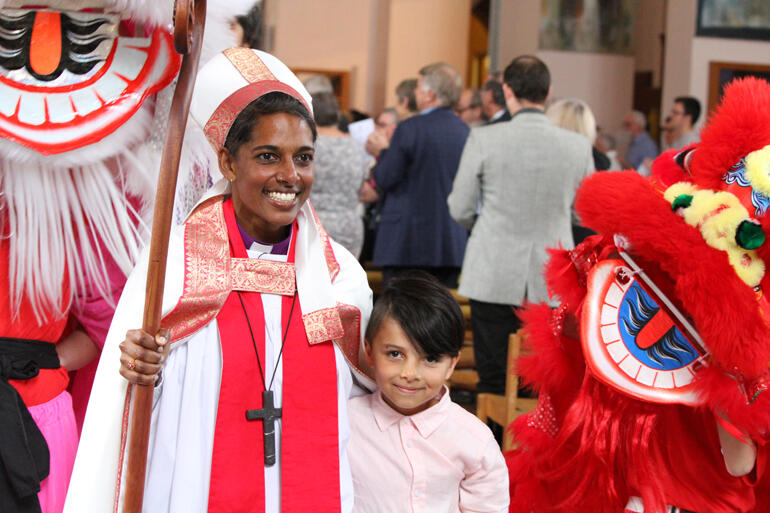 Bishop Ana departs her ordination services accompanied by a troupe of Chinese lion dancers and her son Ishmael.