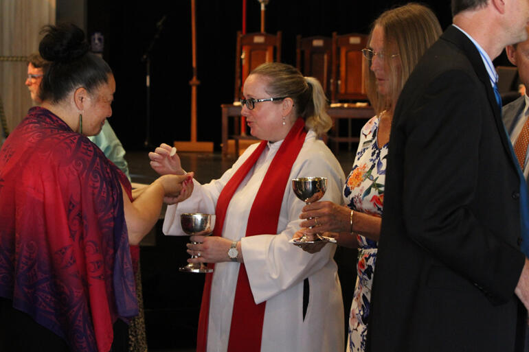 Rev Dr Meg Harvey serves communion to Susan Wallace of Te Waipounamu, who earlier gave the karanga.