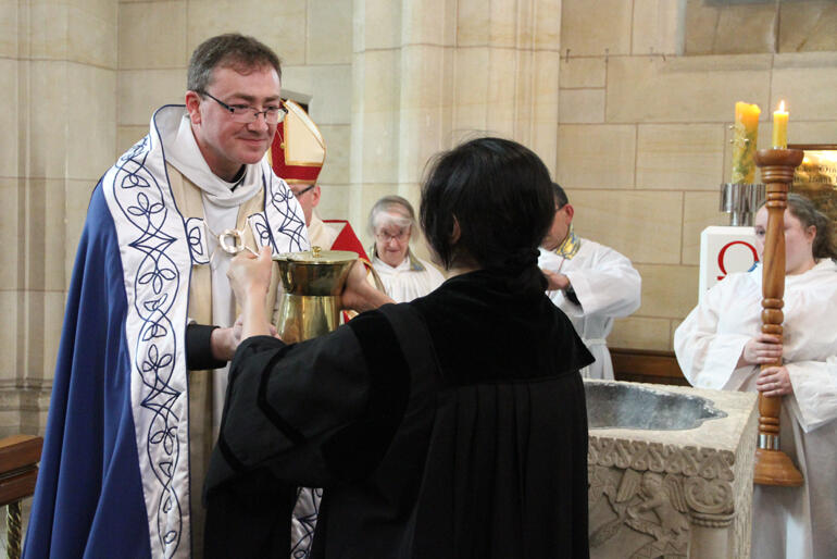 St Paul's Cathedral greeter Mona Tavakoli hands Dean Tony Curtis a ewer of water at the font. 