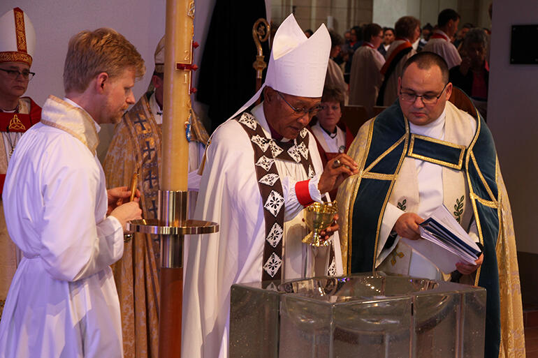 Archbishop Winston blesses the water at the baptismal font. That's Richard Eriksen at left, and Rev Ivica Gregurec. Archbishop Winston blesses the water at the baptismal font. That's Richard Eriksen at left, and Rev Ivica Gregurec.