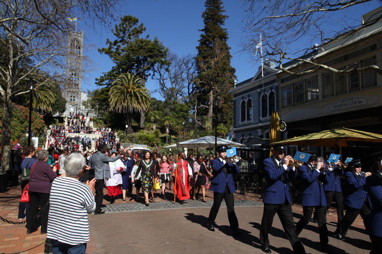 Nelson City Brass Band lead the Bishop and Mayor in procession along Nelson's Trafalgar Street as worshippers pour down the Cathedral steps. 