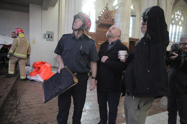 Senior Station Officer Robbie Torrance explains to skylight project manager Tony Burton and Dean Tony how the pinex panels were burnt then soaked.