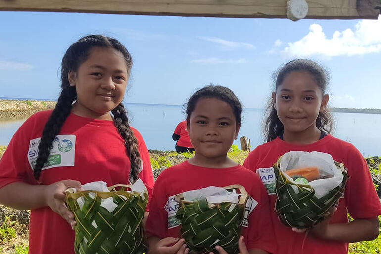 Children taking part in the No Pelestiki campaign show their traditionally woven baskets.